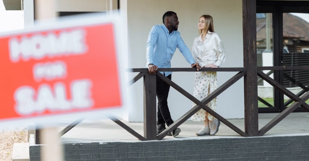 A black man and caucasian woman discussing a property for sale on a porch. Ideal for real estate content.