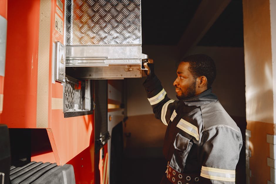 Close-up of a firefighter in uniform working with equipment on a fire truck.
